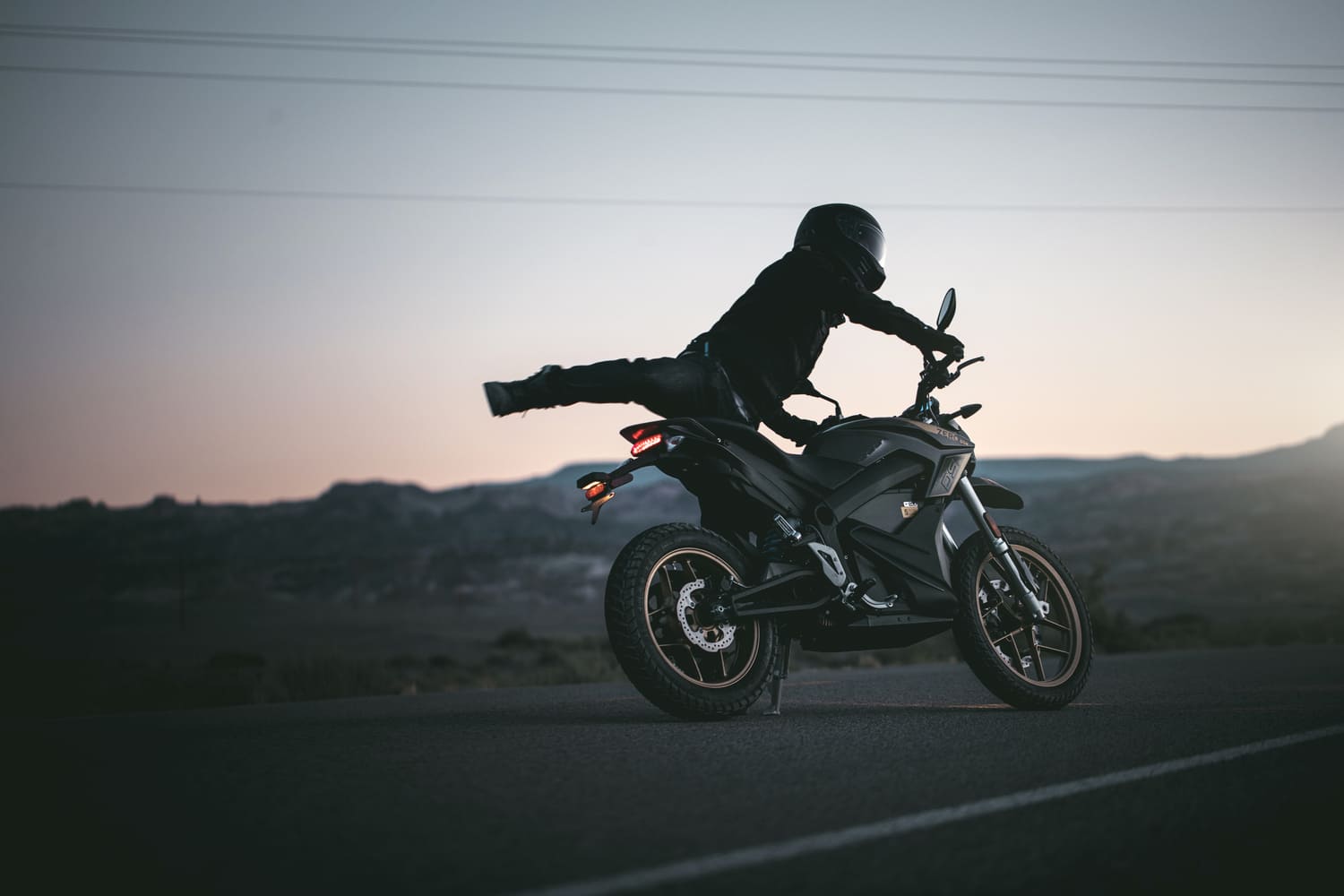 man turning a motorcycle with one leg in the air